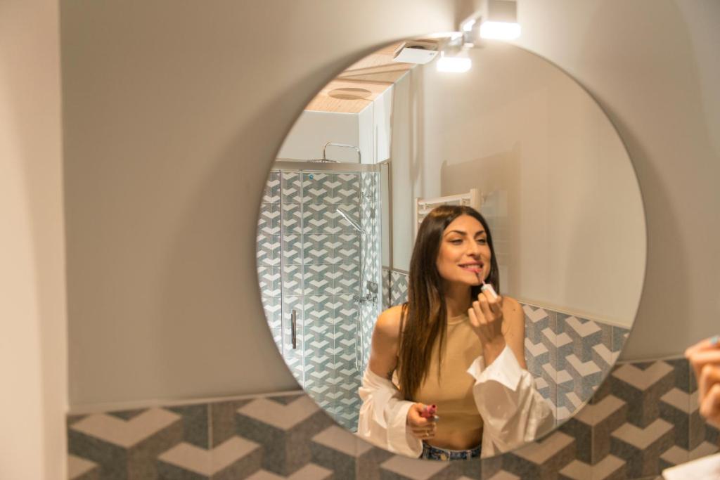 a woman brushing her teeth in front of a mirror at Le Dimore di Puglia - Palazzo Ladogana in Monopoli