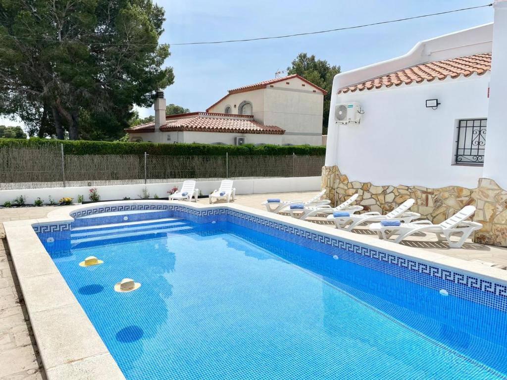 a swimming pool with chairs and a house at Villa Escaleta Costa dorada piscina salina y privada,barbacoa in Les tres Cales
