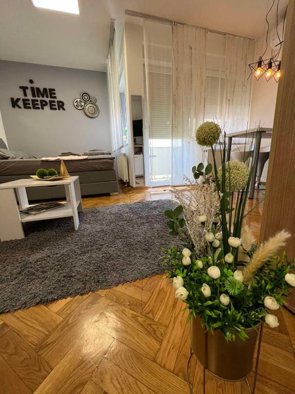 a living room with a vase of flowers on the floor at Time KEEPER in Osijek