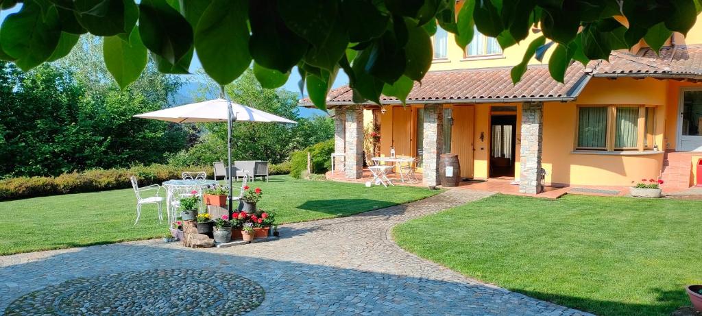B&B Villa Claudia في لافينا بونتي تريسا: منزل مع حديقة فيها مظلة وحديقة