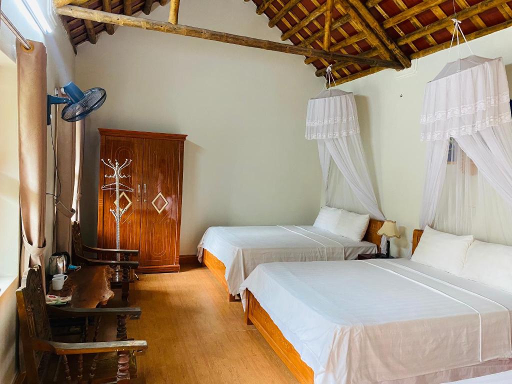 - une chambre avec 2 lits dans une pièce dotée de plafonds en bois dans l'établissement Tam Coc Tropical Homestay, à Ninh Binh