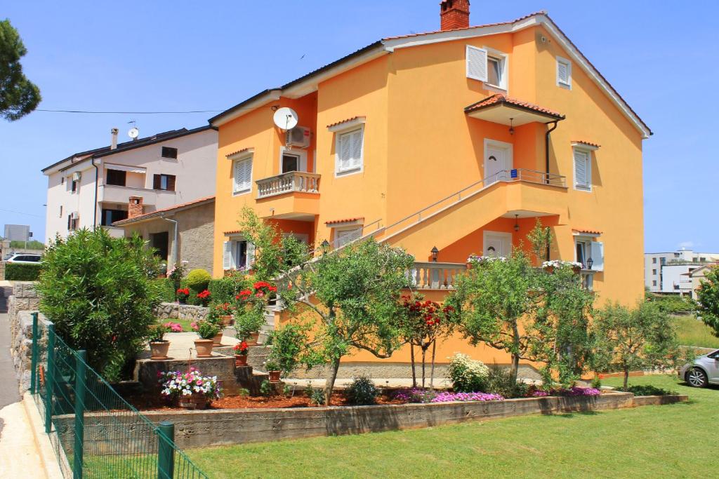 a yellow house with a fence in front of it at Apartmani Mladenka in Malinska