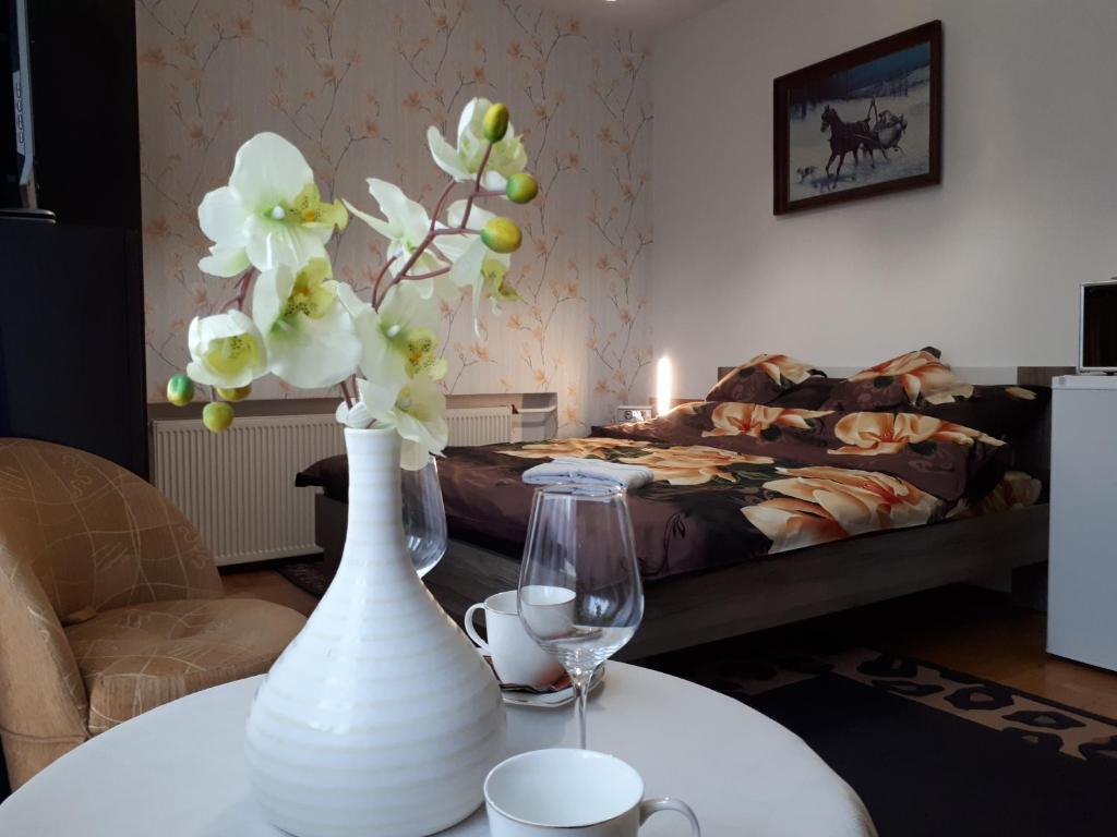 a white vase with flowers on a table with a bed at Dom wczasowy - Ferienwohnung in Ustka