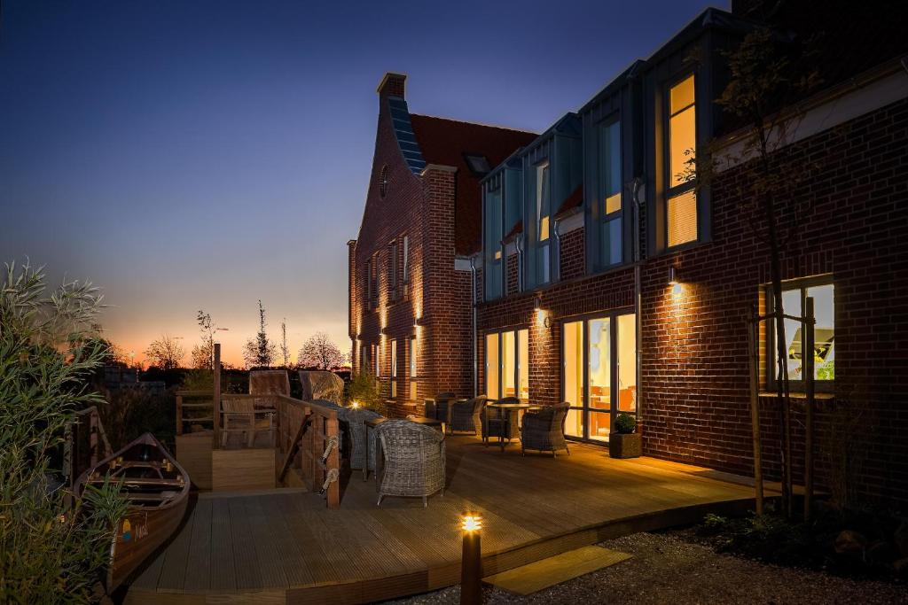 een houten terras met stoelen en een gebouw bij Hotel Grachtenhuus Greetsiel in Greetsiel