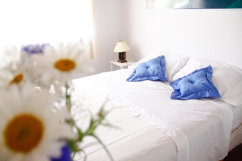 Una cama blanca con almohadas azules y flores. en A Alquiler temporario Arrullo de Luna en Yerba Buena