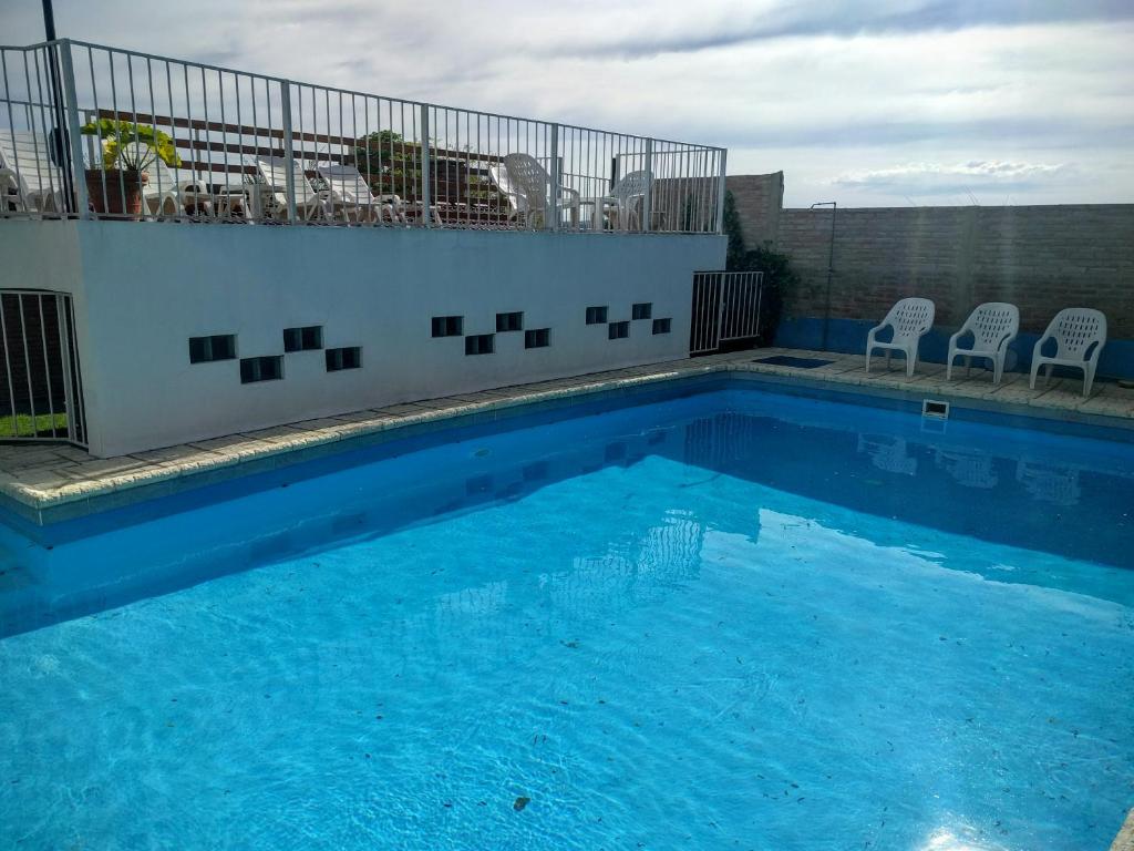 a large blue swimming pool with chairs on a building at Cabañas Bosque in Villa Carlos Paz