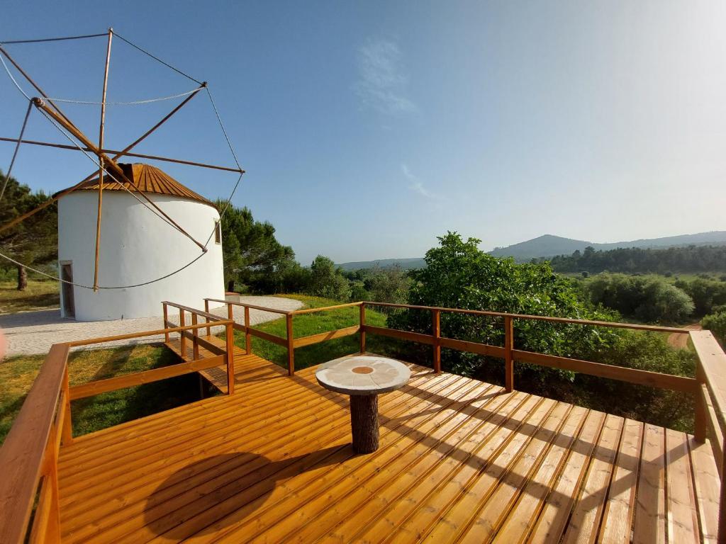 eine Holzterrasse mit einer Bank und einer Windmühle in der Unterkunft Moinho do Cubo in Alvorge