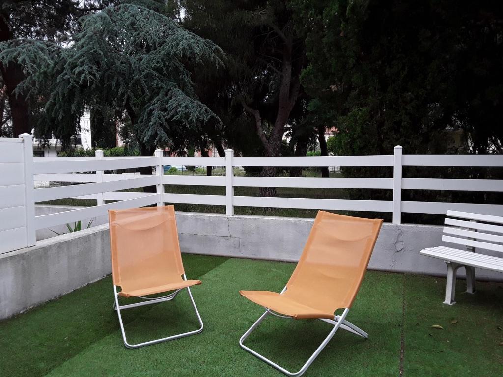 two chairs and a bench in front of a white fence at Studio cocon in Cabestany