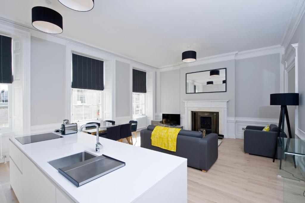 een keuken en een woonkamer met witte muren en een open haard bij Destiny Scotland - Hill Street Apartments in Edinburgh