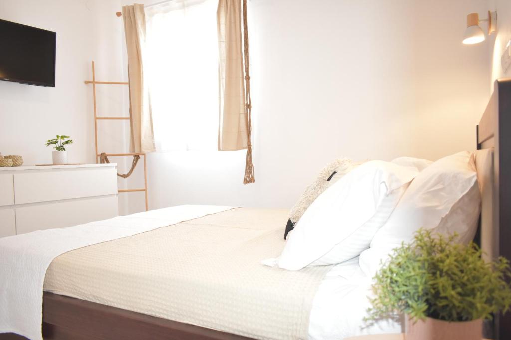 1 dormitorio con 1 cama con sábanas blancas y ventana en ΘΈΑ - THEA Olympos Karpathos en Olympos