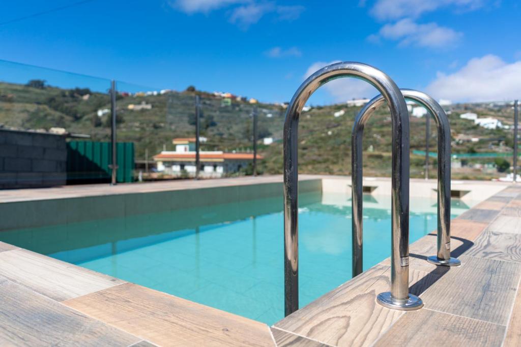 una piscina con barandillas metálicas junto a una piscina en DejaBlue. Villa rural junto al mar y la montaña en Santa Maria de Guia de Gran Canaria