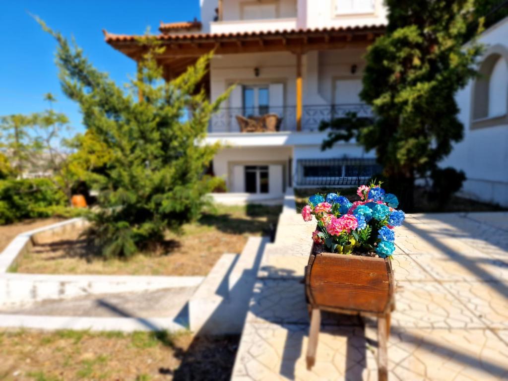 un banco con flores delante de una casa en The Mirador Boutique Villa with Scenic Sea View, en Porto Rafti