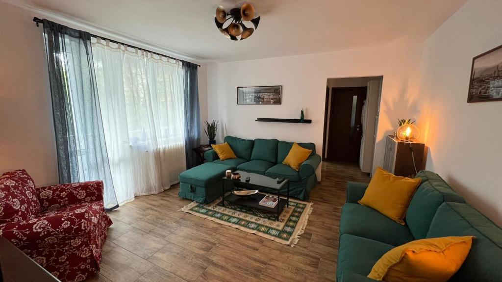a living room with a green couch and yellow pillows at Sunrise apartment in Bistriţa