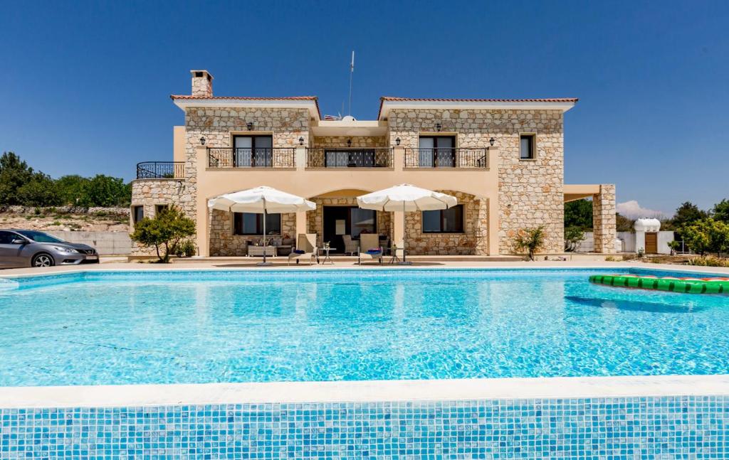 a villa with a swimming pool in front of a house at SunShine Villa Paphos in Nicosia