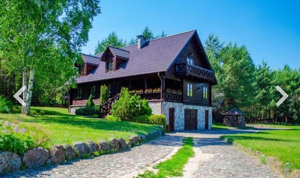 a house with a gambrel roof on a green lawn at WILLA NAD STAWEM MAZURY in Piecki