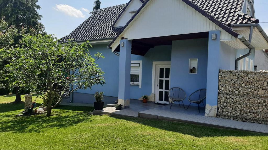 uma casa azul e branca com duas cadeiras num alpendre em Jenny vendégház em Zalakaros