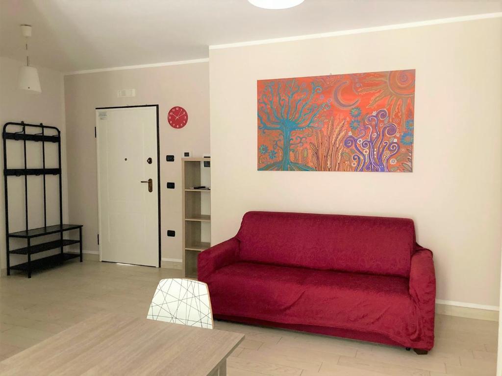 ein rotes Sofa im Wohnzimmer mit einem Gemälde an der Wand in der Unterkunft La Casa del Mare in Sperlonga