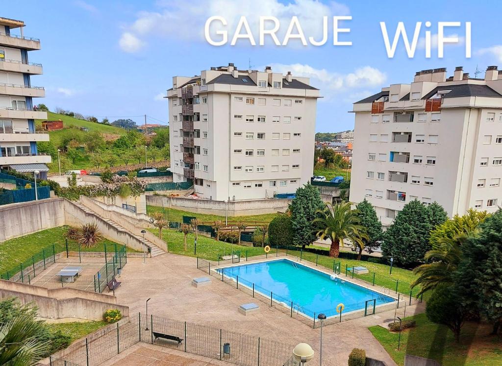 een zwembad in een park met twee gebouwen bij Bonito piso con garaje y piscina a 8 'centro in Castro-Urdiales