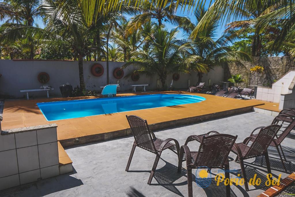 a large swimming pool with chairs and a table at Pousada Porto do Sol in Nova Viçosa