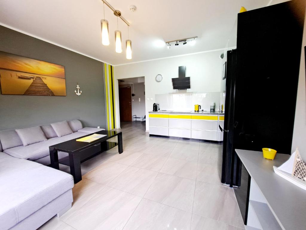 a living room with a couch and a kitchen at Port Yellow in Giżycko
