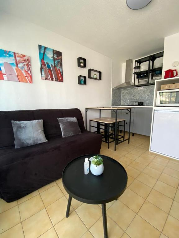 - un salon avec un canapé noir et une table dans l'établissement Petit T2 proche de la plage, à Sète