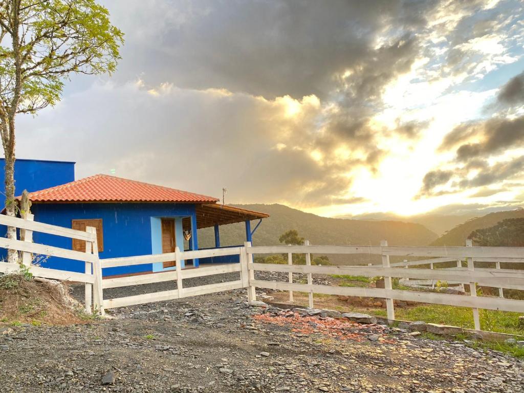 una casa azul con una valla blanca en un campo en Meu Cantinho Serrano, en Urubici