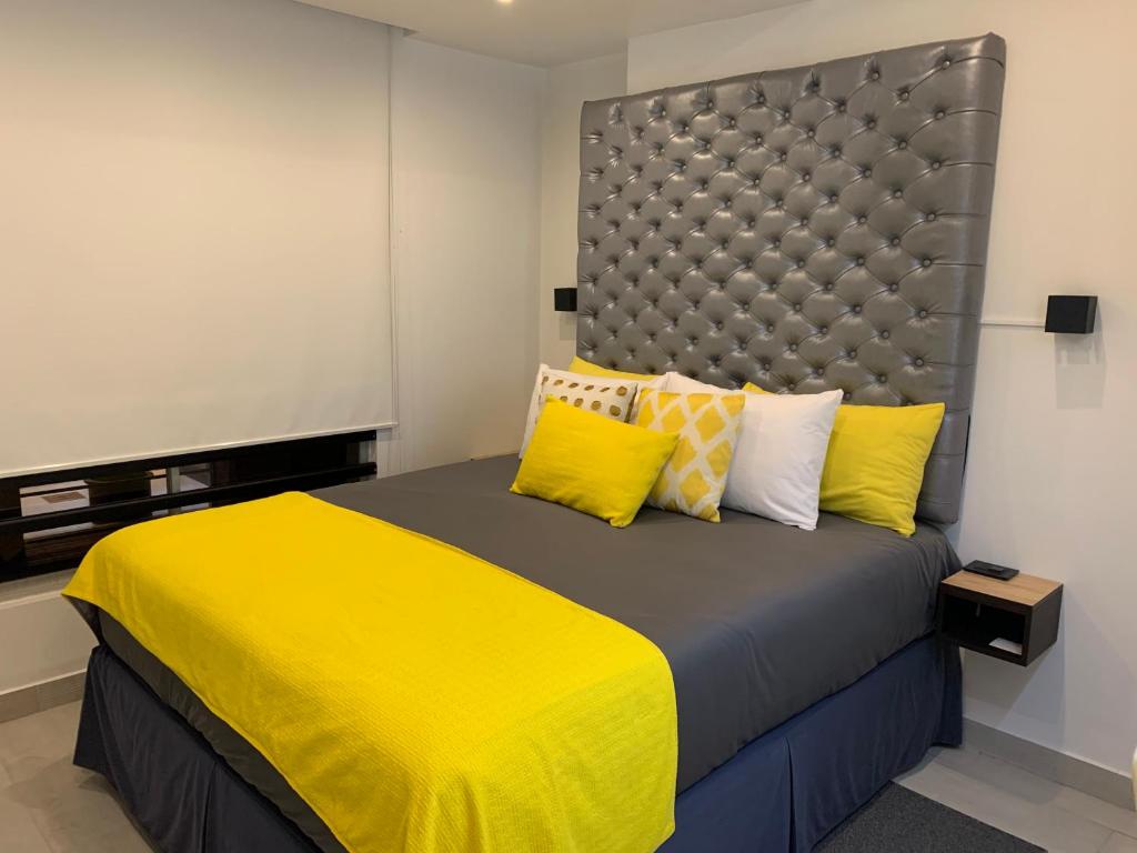 1 dormitorio con 1 cama grande con almohadas amarillas en PARQUE REAL SUITE, en Quito