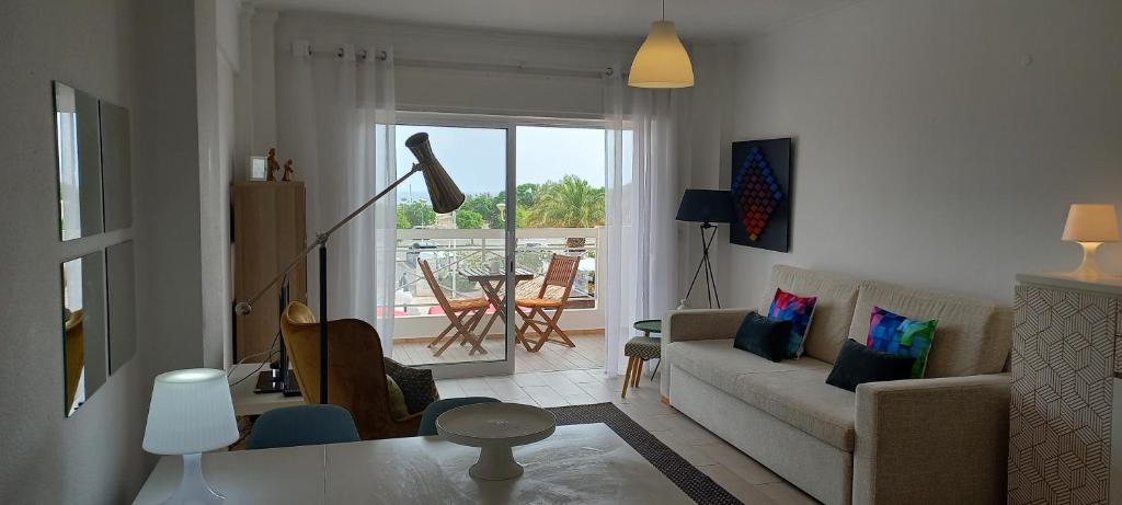 ein Wohnzimmer mit einem Sofa und einem Tisch in der Unterkunft Apartamentos Dom Henrique in Monte Gordo