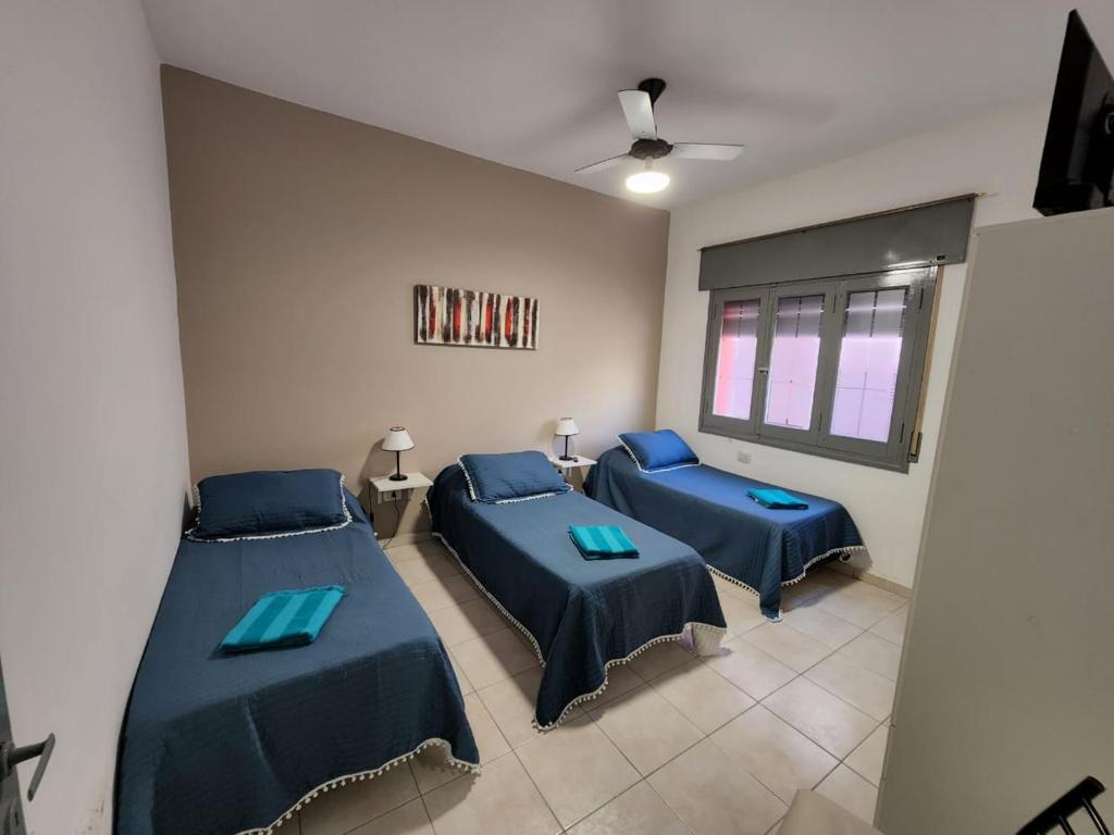 Dos camas en una habitación con sábanas azules. en Departamentos HF, en Villa María