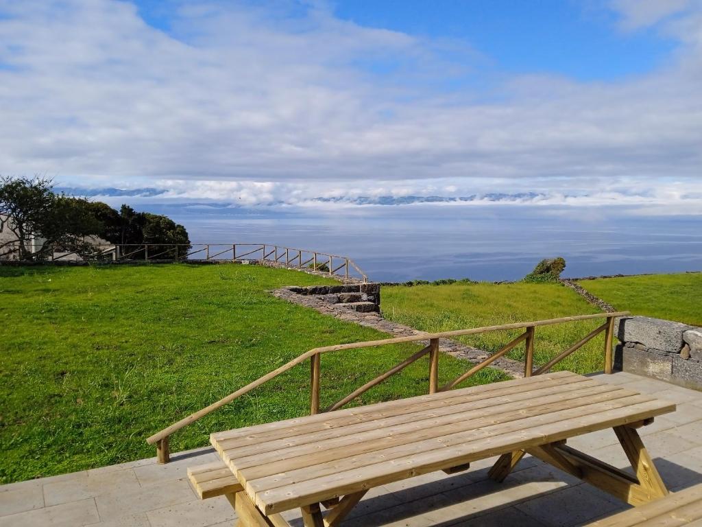 un banco de madera sentado en la cima de una colina con césped en Casa da Ribeirinha, en Ribeirinha