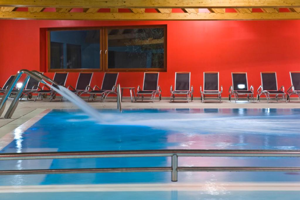 a swimming pool with a slide in a room with chairs at Garda Sporting Club Hotel in Riva del Garda