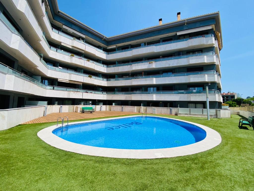 um grande edifício com uma piscina em frente em RELAX APARTAMENTO Playa Fenals em Lloret de Mar