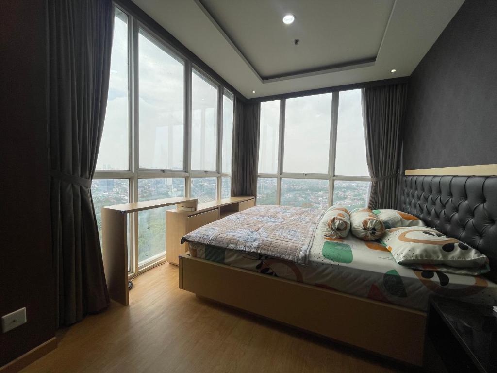 um quarto com uma cama e um monte de janelas em 2BR Lovely Condo Amazing City View Lexington Residence em Jakarta