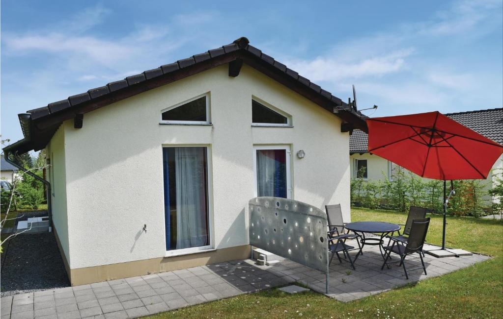 una casa con una mesa y una sombrilla roja en Lovely Home In Gerolstein-hinterhaus, With Kitchen, en Hinterhausen