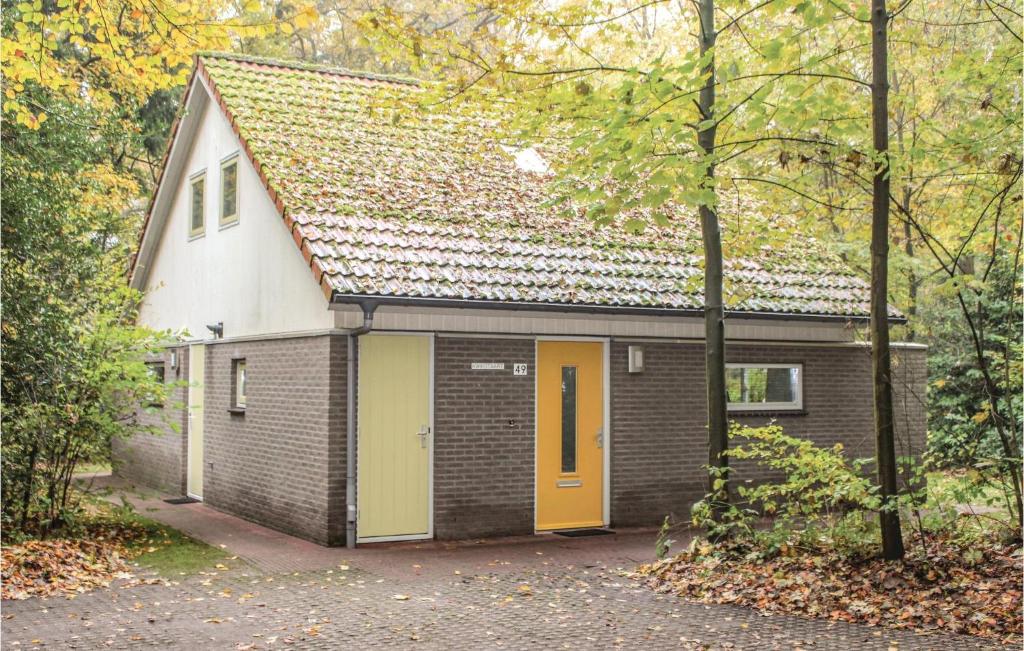 uma pequena casa de tijolos com uma porta amarela em Kwikstaart em Oudemirdum