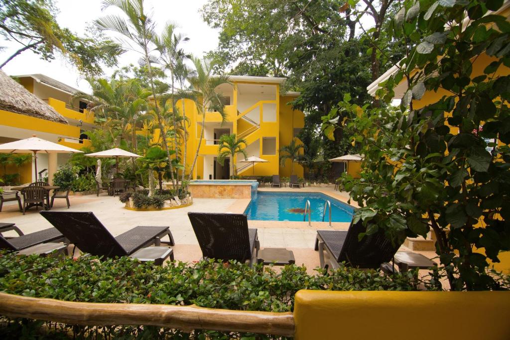 un complexe avec une piscine, des chaises et un bâtiment dans l'établissement Hotel Chablis Palenque, à Palenque