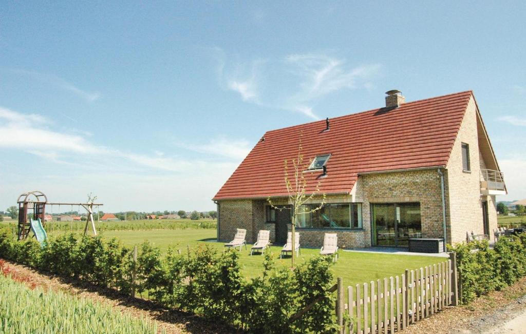 a brick house with a red roof and a playground at Lieke in Poperinge