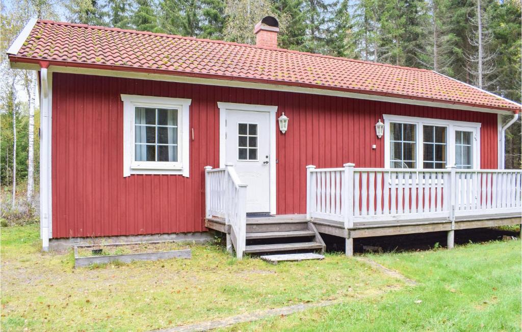 una casa roja con porche y valla blanca en Nice Home In Eksj With Kitchen en Eksjö