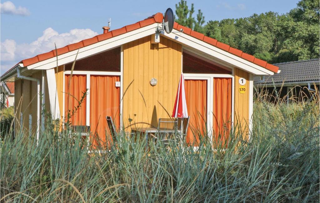 een huis met oranje deuren en stoelen in een veld bij Schatzkiste 1 - Dorf 4 in Travemünde