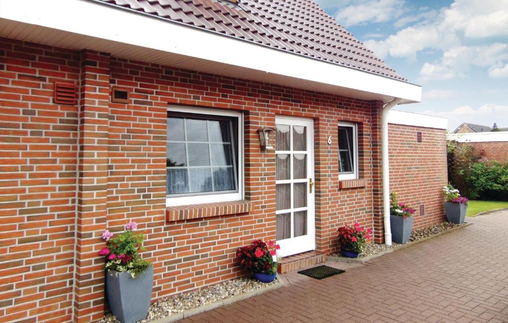 une maison en briques avec deux fenêtres et des plantes en pot dans l'établissement Lovely Home In Wittmund-altfunnixsiel With Kitchen, à Altfunnixsiel