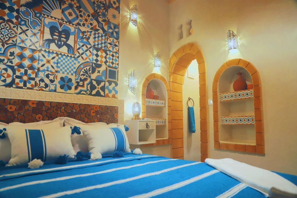sypialnia z 2 łóżkami i białymi i niebieskimi poduszkami w obiekcie Riad Milal w mieście As-Suwajra