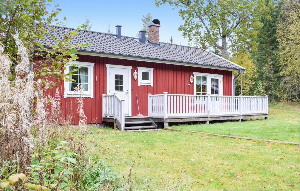 une maison rouge avec une terrasse couverte blanche et une cour dans l'établissement 2 Bedroom Lovely Home In Eksj, à Eksjö