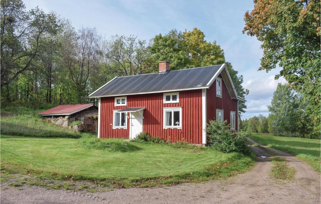 a red barn in a field with a dirt road at 2 Bedroom Nice Home In senhga in Åsenhöga