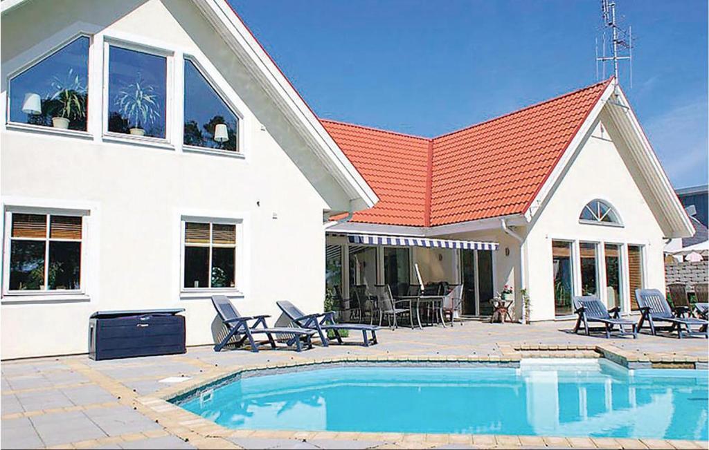 a house with a swimming pool in front of a house at Beautiful Home In Nybrostrand With 5 Bedrooms, Private Swimming Pool And Outdoor Swimming Pool in Glemminge