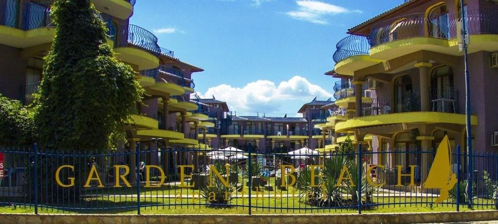 a fence in front of a yellow building at Къмпинг градина луксозен апартамент in Chernomorets