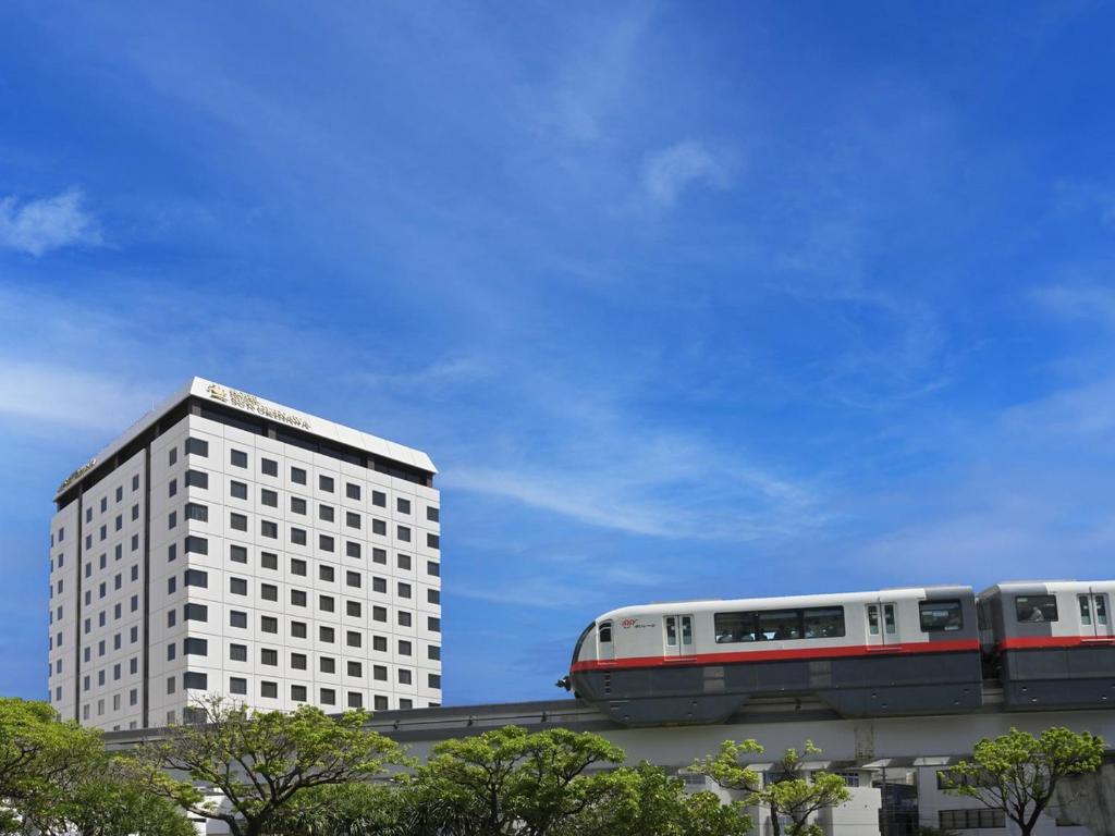 a train traveling past a tall white building at Hotel Sun Okinawa in Naha