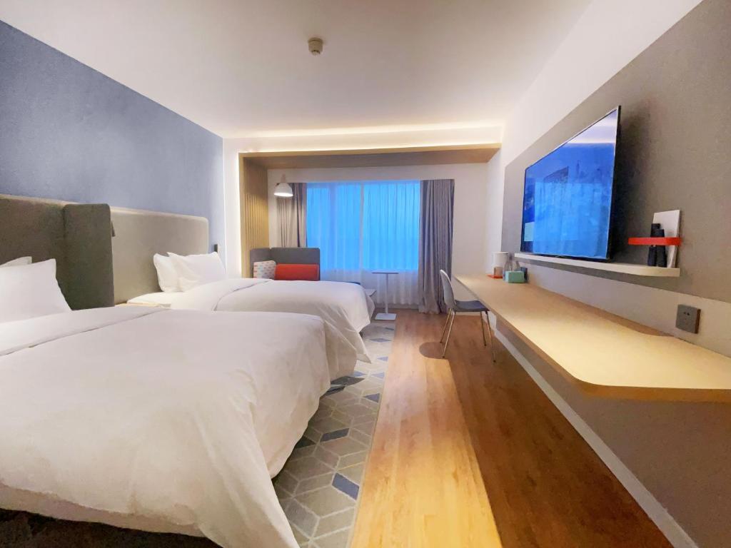 Holiday Inn Express Hohhot East Station, an IHG Hotel في هوهوت: غرفة فندقية بسريرين وتلفزيون بشاشة مسطحة