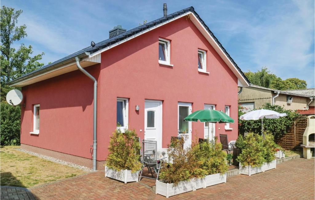 ein rotes Haus mit einem Tisch und einem Regenschirm in der Unterkunft Amazing Apartment In Khlungsborn With 1 Bedrooms And Wifi in Kühlungsborn