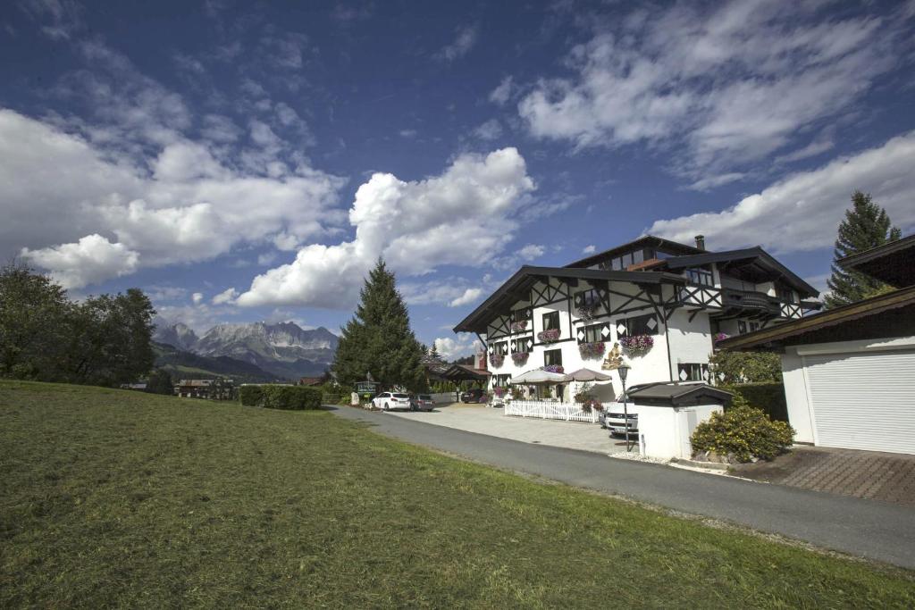 ein Haus mit einem Rasenplatz neben einem Gebäude in der Unterkunft Hotel Garni Zimmermann in Reith bei Kitzbühel