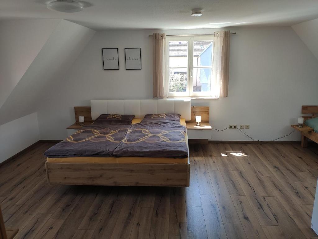 1 dormitorio con cama, ventana y suelo de madera en Ferienwohnung Barner - KEINE MONTEURE en Owen